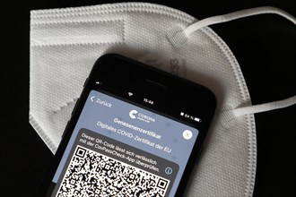 FFP2 mask and iPhone with Corona warning app with QR code for certificate of recovery