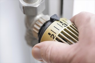 Hand turns the heating thermostat