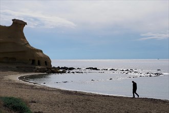Lonely man walking on lonely beach in front of sparkling sea