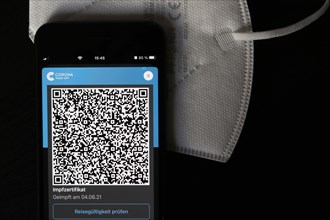 FFP2 mask and iPhone with Corona warning app with QR code for vaccination certificate