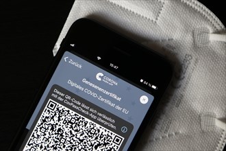 FFP2 mask and iPhone with Corona warning app with QR code for certificate of recovery