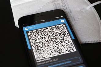 FFP2 mask and iPhone with Corona warning app with QR code for vaccination certificate