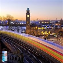 Atmospheric light trails of moving elevated railway and clock tower at sunrise