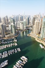 Dubai Marina and Harbour luxury wealth holiday with boats yacht from above in Dubai