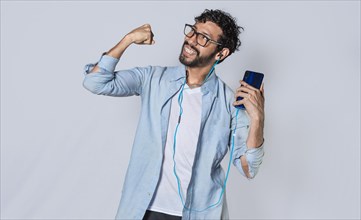 Happy man with headphones holding a cell phone and celebrates