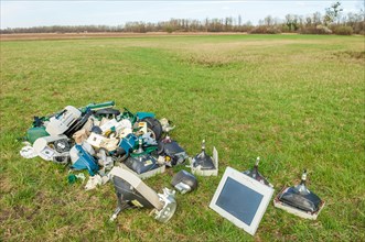 Polluting plastic waste and computer scrap illegally disposed of in a meadow