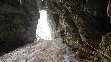 Young man climbing in a via ferrata in a rock hole