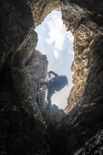 Young woman climbing a steep rock face