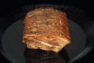 Crispy roasted pork belly lies in an iron pan