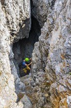 Young man climbing out of a rock hole