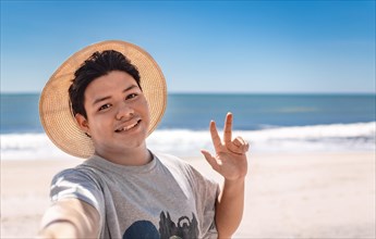 Young man taking a selfie portrait on the beach