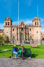 Two men talking on a bench in front of the Cusco Cathedral