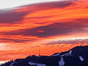 Clouds above the summit of the Mugel in the morning red at sunrise