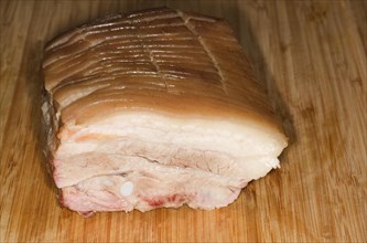 Pre-cooked pork belly on wooden board