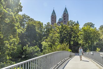 Woman walking over bridge at Speyerbach towards cathedral