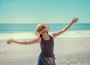 Woman in hat happy on the beach