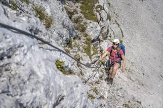 Young woman climbing a steep rock face