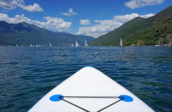 View from the standup paddle board on sailboats and mountains at Lake Maggiore