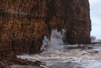 Winter storm whips waves and spray against the red sandstone rocks on the northern beach