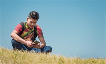 Backpacker with phone on top of a hill