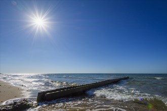 Wooden Breakwater on the Beach with Sun