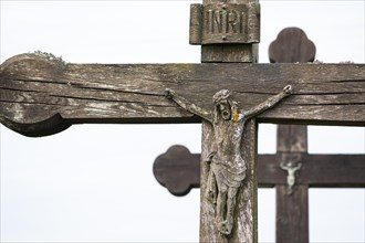 Wooden figure of Jesus on a weathered and lichen covered wooden cross