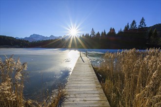 Wooden jetty with frozen lake and sun