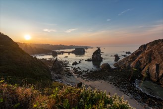 View of sea and sandy beach Harris Beach with rocks at sunrise