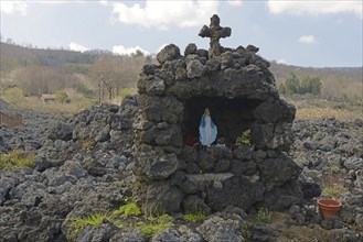 Lava rock and statue of the Virgin Mary at the foot of Mount Etna