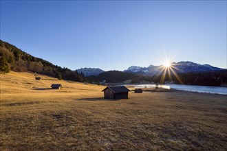 Sunrise over Karwendel mountain range with frozen lake and hay barn