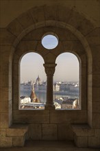 View through an arched window of the Fishermen's Bastion onto the Danube with the Parliament Building