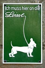 Old sign with dachshund on a leash