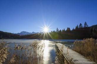 Wooden jetty with frozen lake and sun