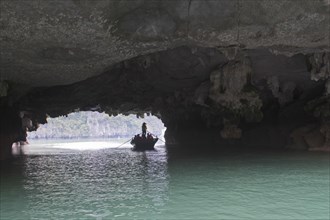 Rowing boat at the rock tunnel in Halong Bay
