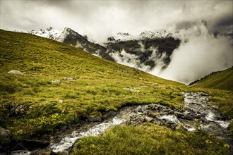 Mountain stream with mountain landscape and dramatic clouds