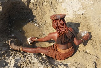 Himba woman collecting water at a water hole
