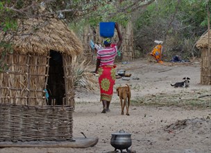 A woman carries water from a nearby river to her hut