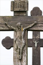 Wooden figure of Jesus on a weathered and lichen-covered wooden cross