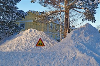 Huge snow piles and traffic sign with snowmobile in front of residential buildings