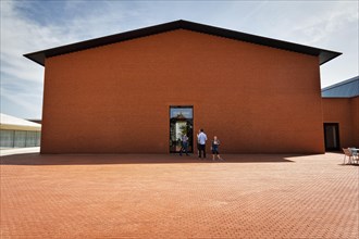 Visitors in front of building made of red bricks in the shape of a warehouse