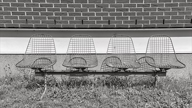 Four wire chairs in front of a wall