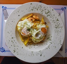 Fried eggs with potatoes and prawns in garlic