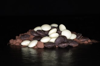 Dark and white couverture chocolate drops lying on cocoa powder