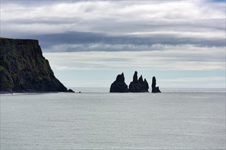 Cloudy sky over cliff with rock needles Reynisdrangar in summer