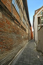 Extremely narrow alley with old brick wall