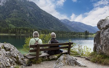 Women hikers sitting on a wooden bench at Hintersee
