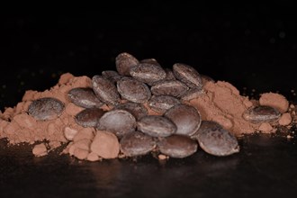 Dark couverture chocolate drops lying on cocoa powder