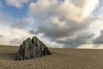 Rock spire on sandy surface