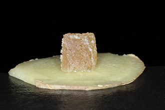 Candied ginger cut into cubes lies on a slice of fresh ginger
