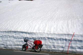 Bicycle with a lot of luggage standing in front of high snow walls